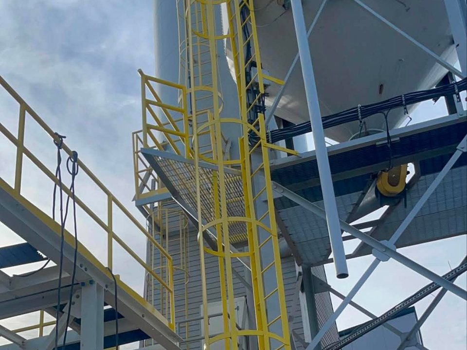 Worker on an elevated lift beside industrial equipment